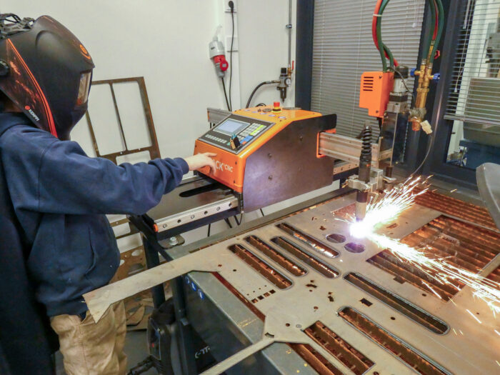 Peruskoulun oppilas käyttää  cnc-plasmaleikkuria Ylihärmässä.